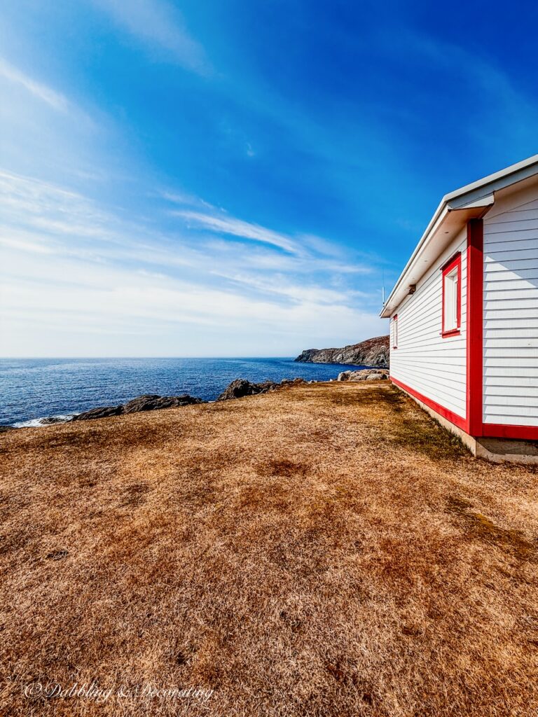 Red and white house overlooking the Atlantic Ocean from a Cliff in Saint Anthony Newfoundland.