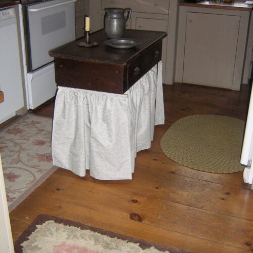 Decorating with family heirlooms; Antique kitchen center small table with pewter and handmade curtains wrapped around the bottom in country kitchen. An old fashioned photo!