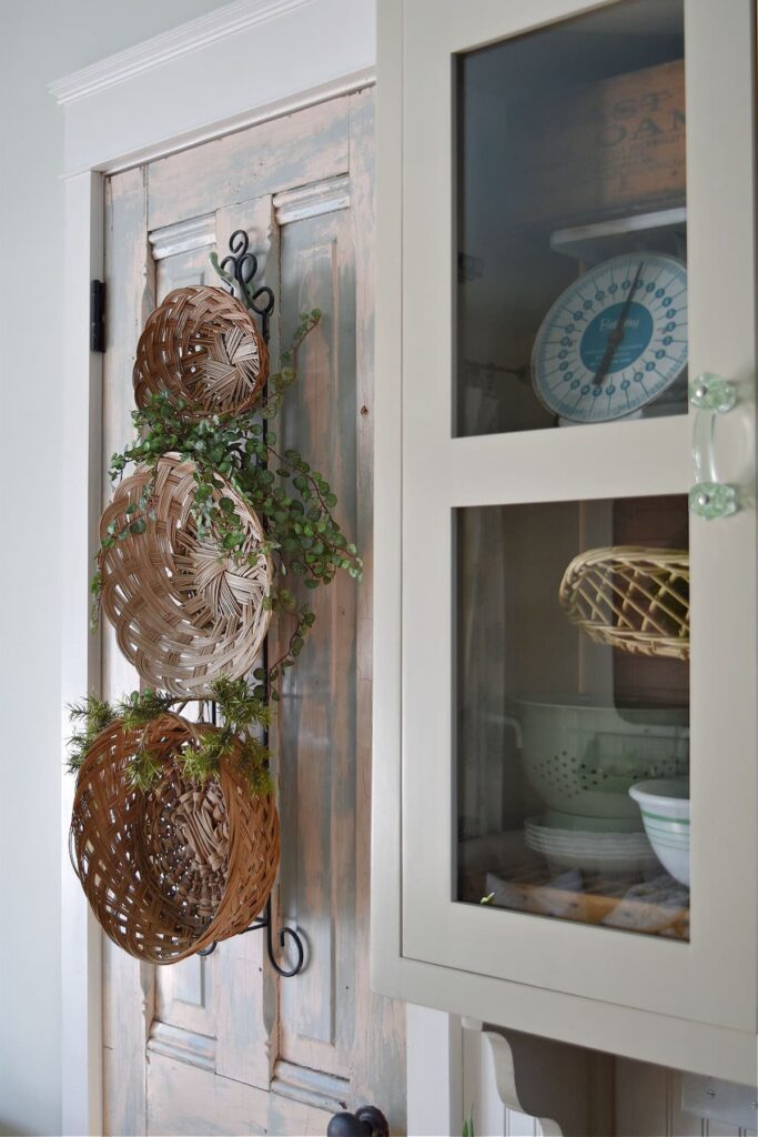 Three vintage baskets hanging on a wall next to cabinet.
