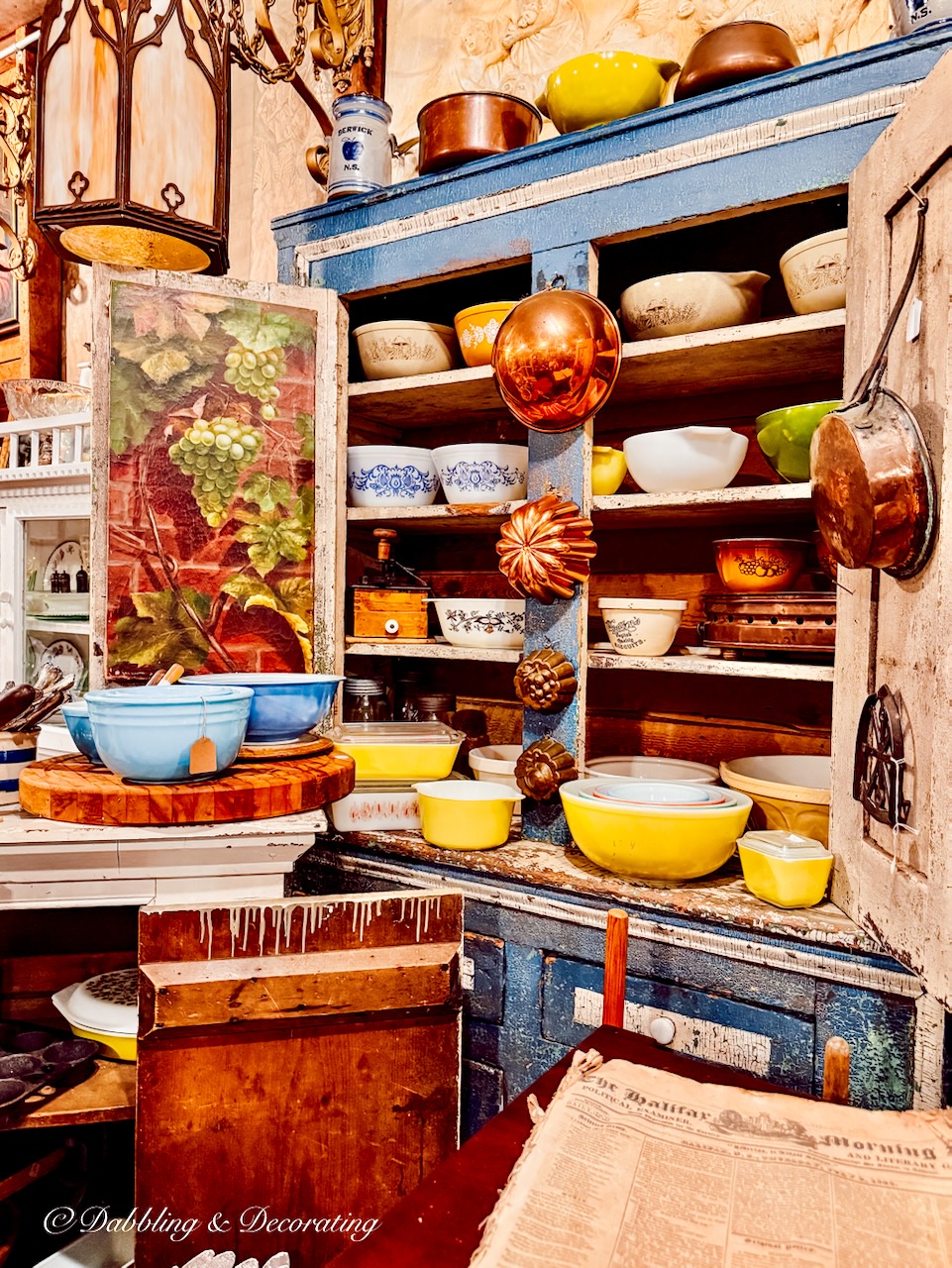Antique blue hutch in antique store with vintage colorful bowls.