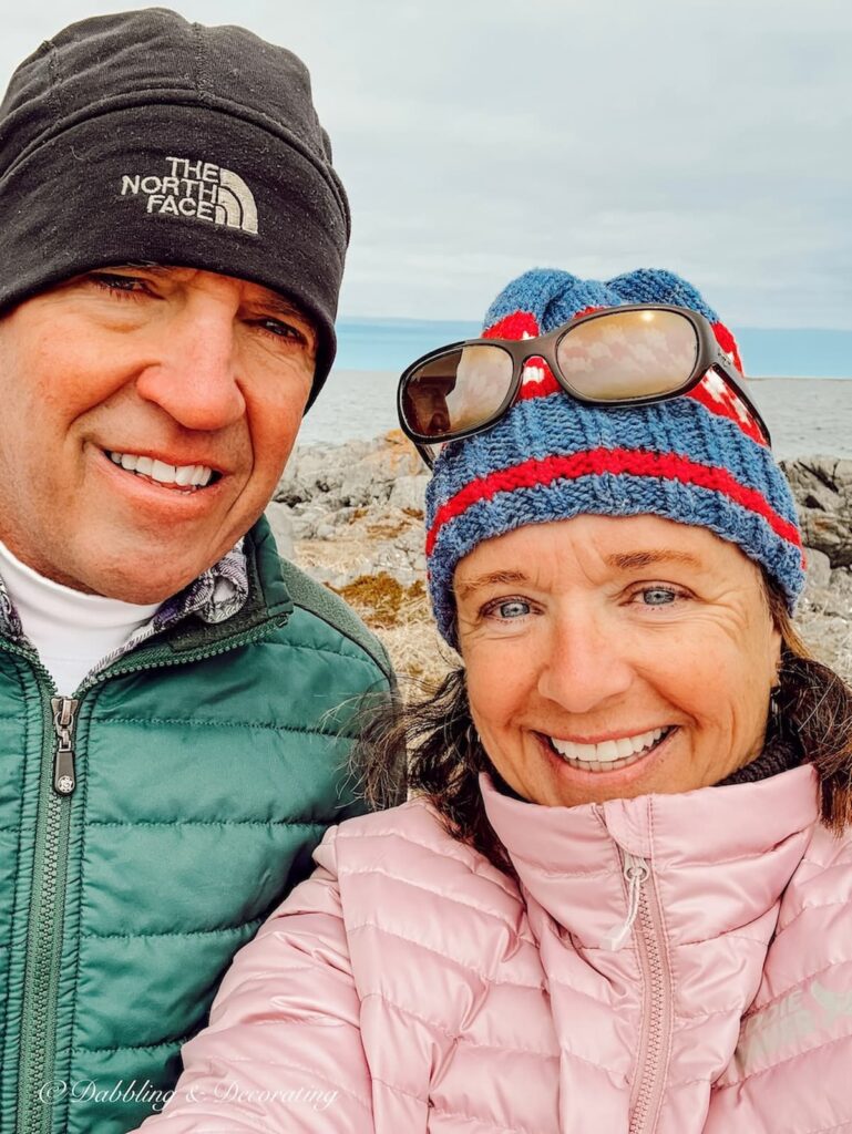 Man and Woman with knit hats and coats at the beach selfie.