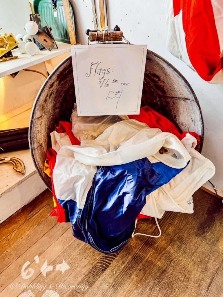 A bucket displaying red, white, and blue maritime flags in antique shop in Nova Scotia as coastal cottage décor ideas.