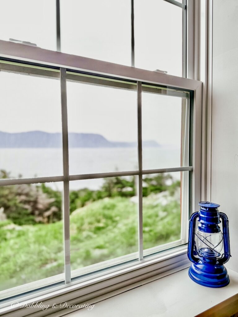 Vintage blue lantern sitting on white windowsill in lighthouse in coastal cottage décor ideas.