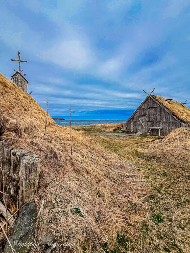 Norstead village with church and house with thatched roofs on Newfoundland's coastal beach.