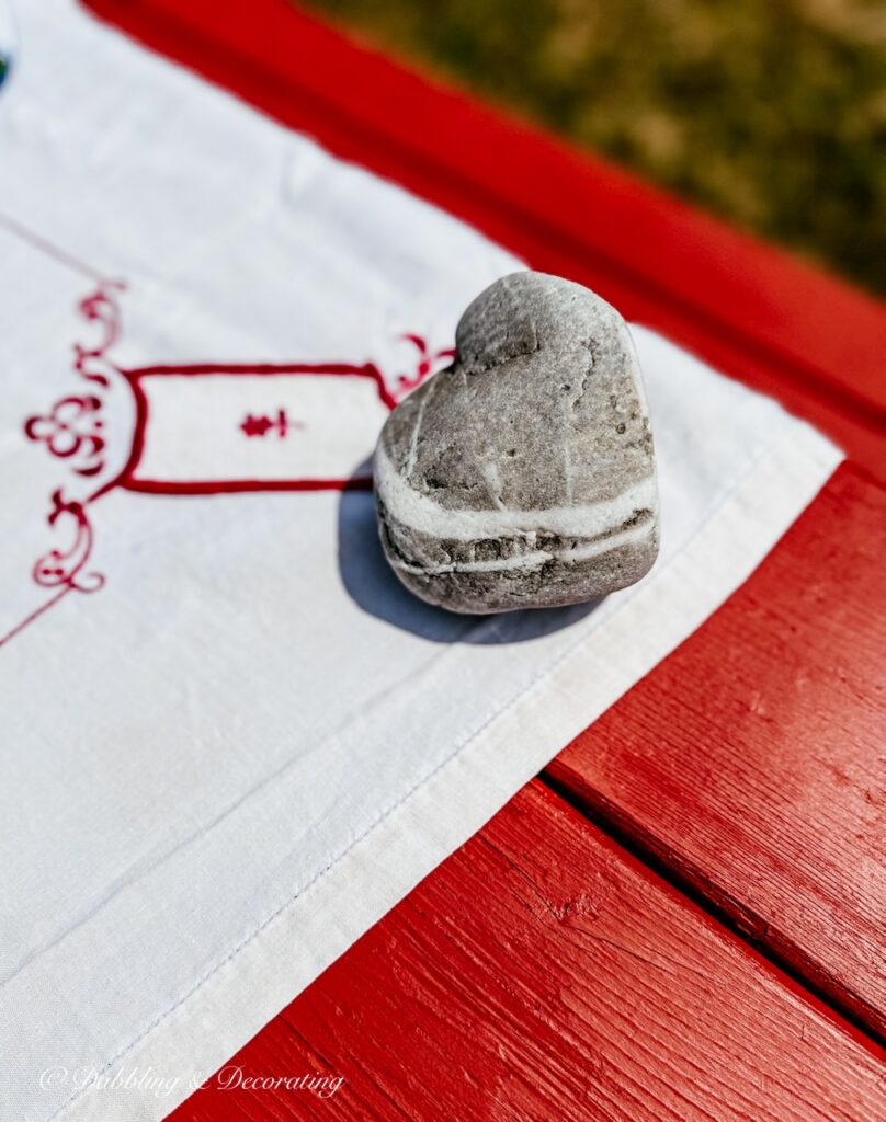 rock shaped as a heart of red picnic table holding tablecloth outside.