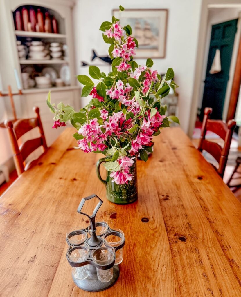 Pink flowers in green McCoy pitcher in vintage styling dining room as table centerpiece for summer decor.