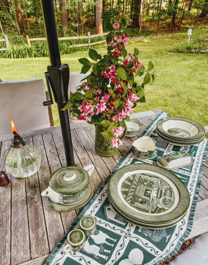 Green and white summer decor finds on outdoor teak table setting.