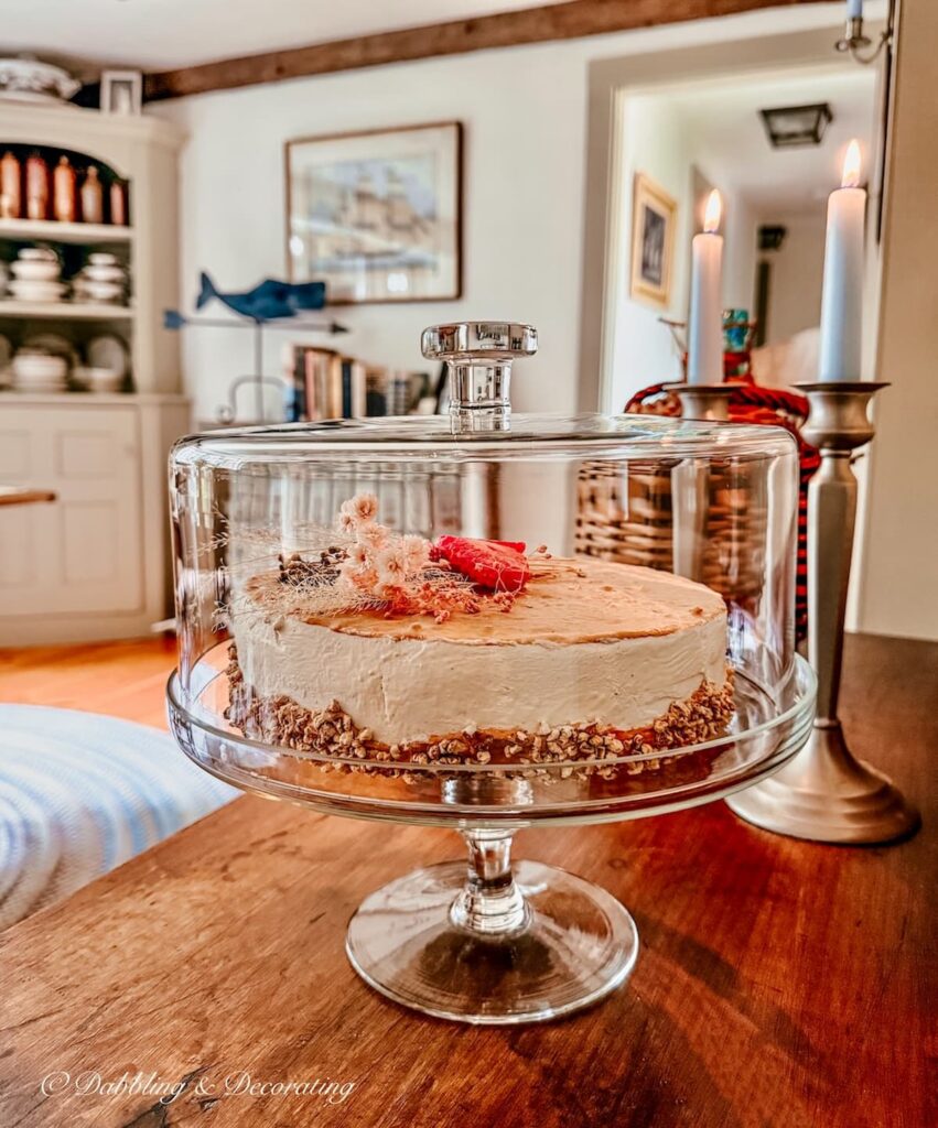 Summer decor finds, a glass cake stand with a globe on antique table with candles and pink cake.