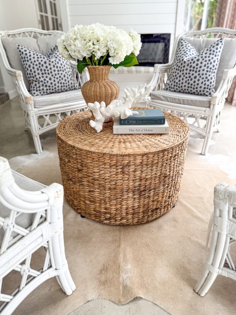 White cottage style porch with wicker ottoman and white wicker seating in Florida home.
