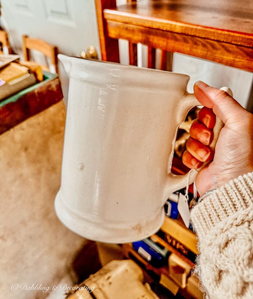 Vintage white ironstone pitcher in hand for coastal vintage decor charm.