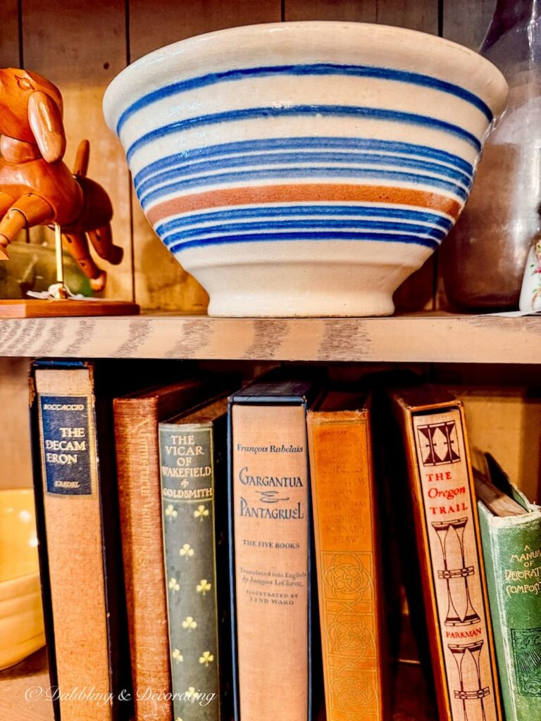 Blue and brown collectible cornishware bowl on shelf in antique store with vintage books.