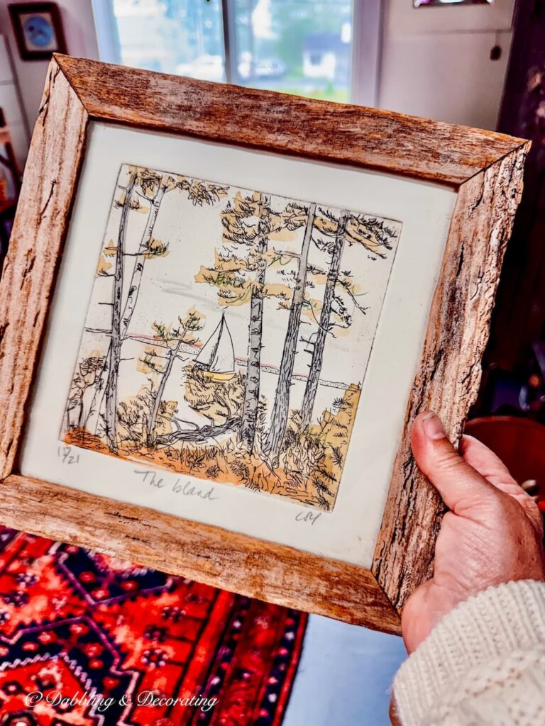 Driftwood framed sailboat picture in hand for vintage coastal decor bedroom.