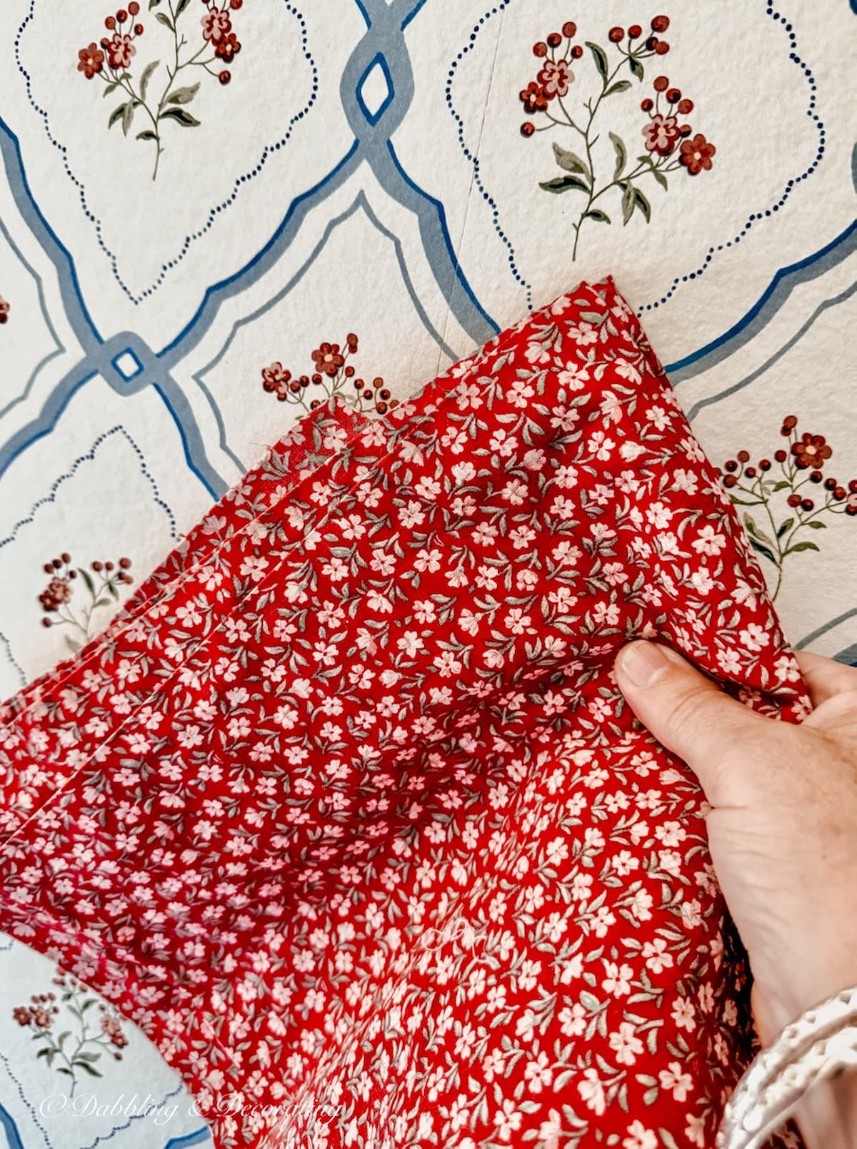 Red vintage floral curtain material next to vintage style blue and floral red wallpaper.