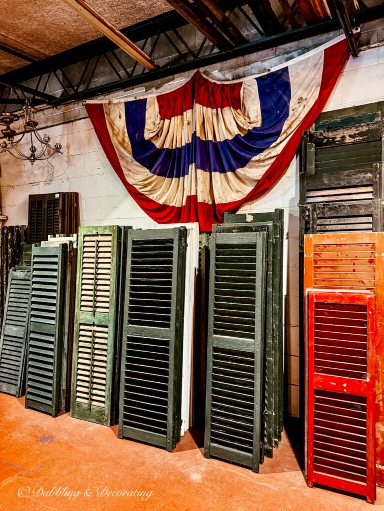Green shutters stacked at The Old House Parts Co. with USA Bunting hanging on wall.