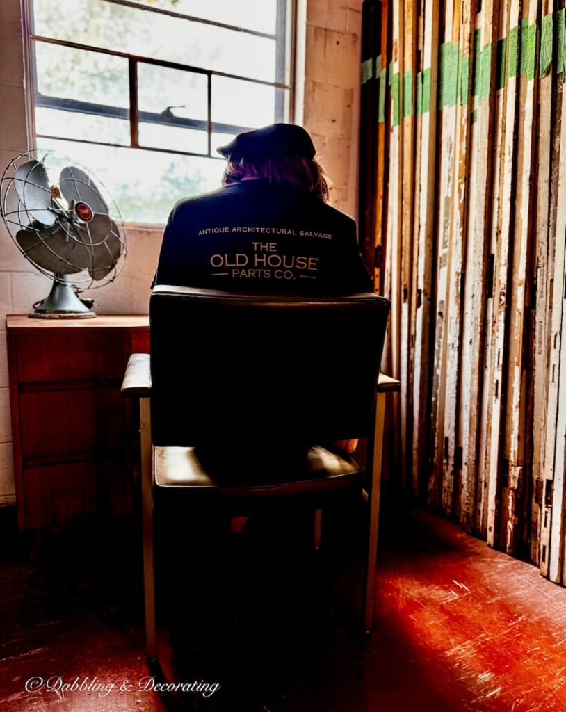 Vignette of a mannequin sitting at a window in The Old House Parts Co. with fan on second floor.