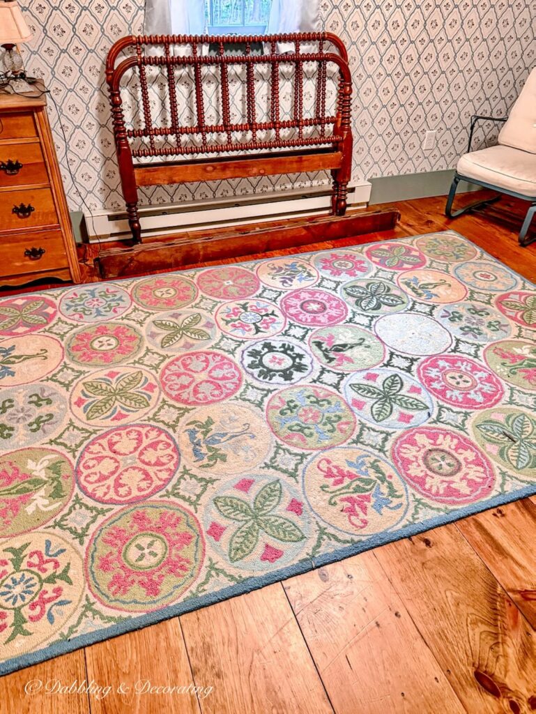 Antique Jenny Lind bed leaning against bedroom wall with colorful rug on wood flooring in small guest bedroom