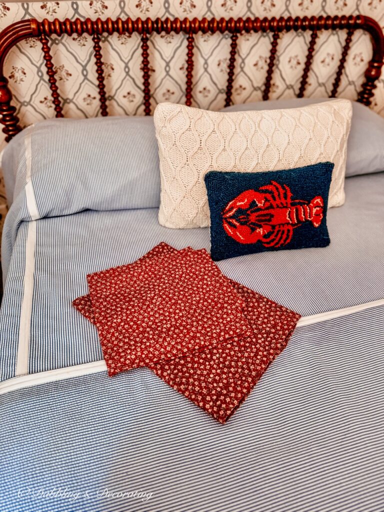 Blue and white seersucker bedding on Jenny Lind Bed Makeover with red home made valances laid out with lobster pillow.