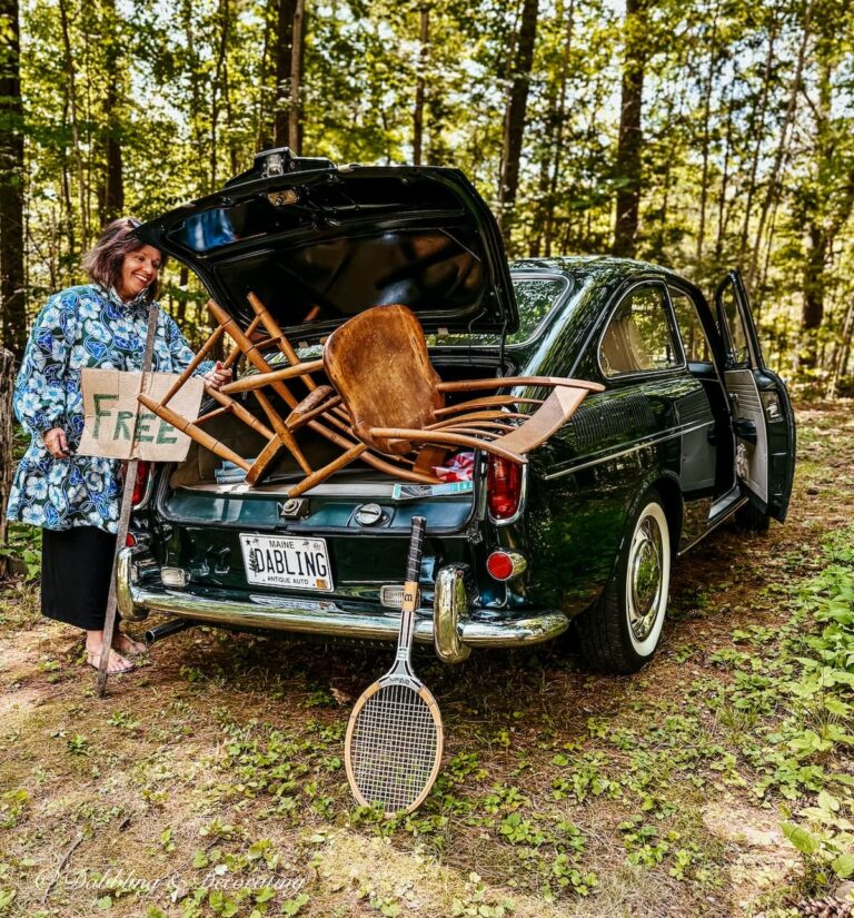 Ann vintage home decor blogger looking into back of vintage VW car on a thrift store road trip with wooden chairs, tennis racket and Free sign.