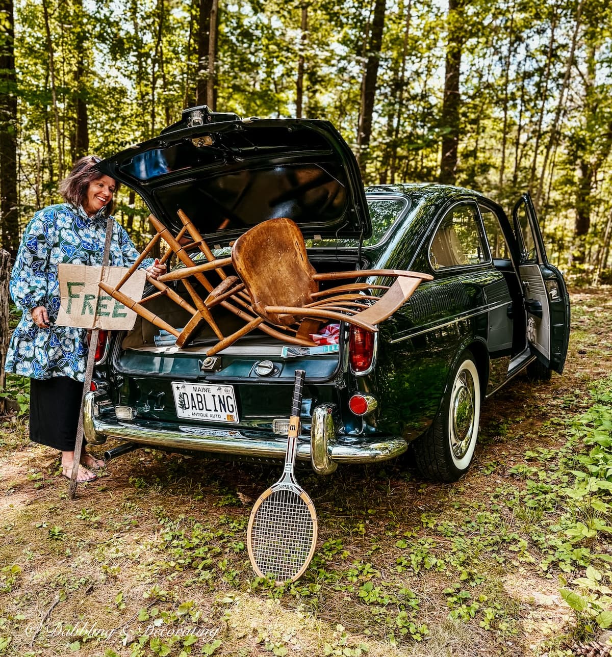 Ann vintage home decor blogger looking into back of vintage VW car on a thrift store road trip with wooden chairs, tennis racket and Free sign.