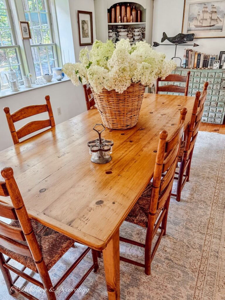 Antique pine rectangular table with six ladder back chairs and a basket of limelight hydrangeas. Eclectic Decorating Style.