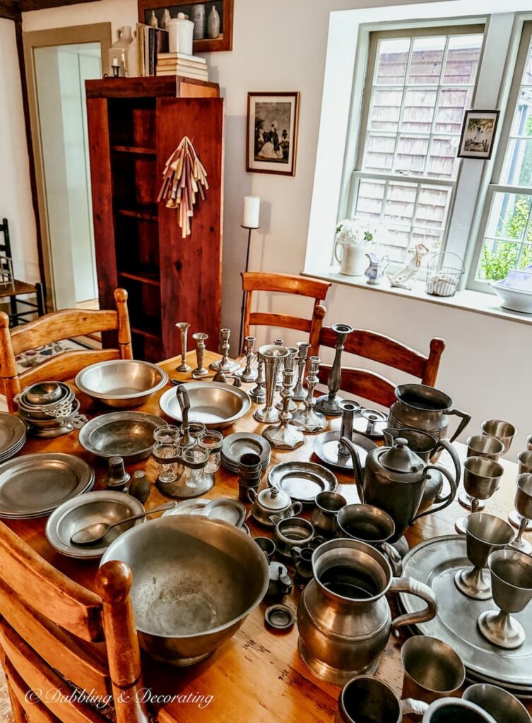 Antique pewter collection scattered across dining room table ready to style an antique hutch.