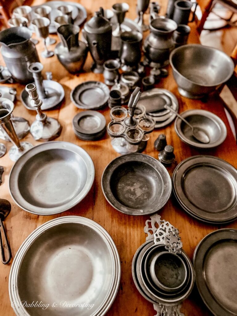 Antique pewter collection organized by style across large pine table.