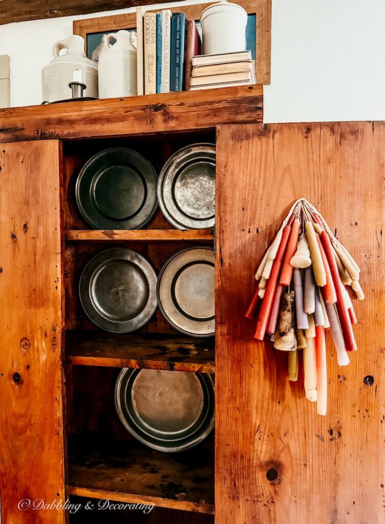 How to style an antique hutch with pewter, layering plates first.