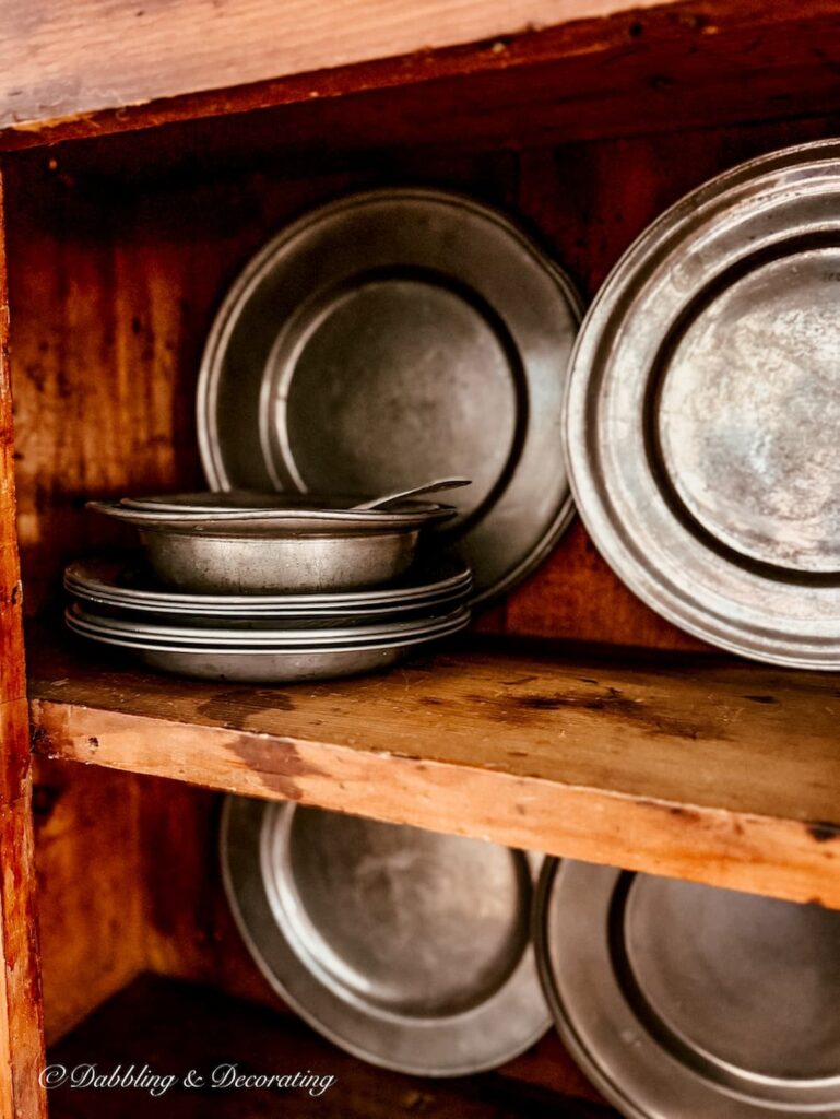 Antique hutch with pewter plates layered with pewter bowls in how to style and antique hutch with layers.