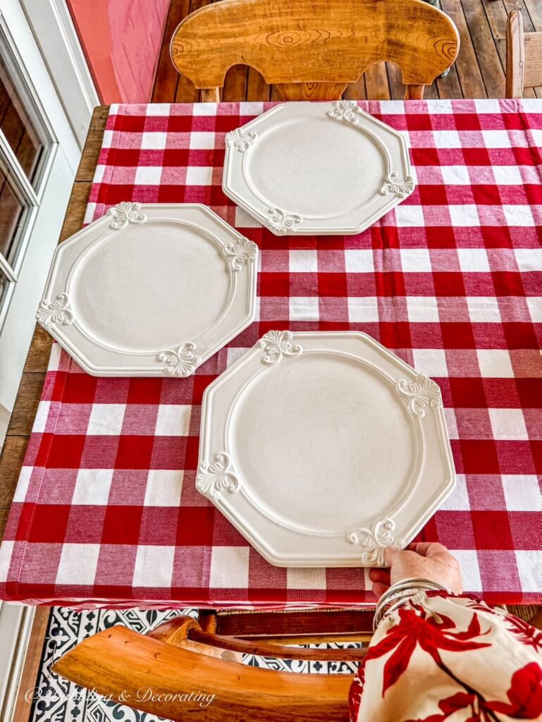 Fall table decor with red gingham table cloth and thrifted Goodwill charger plates on outdoor porch tablescape.