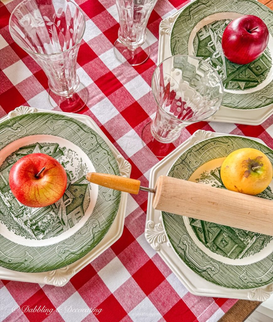 Cozy thrifted green and white table place settings on red gingham tablecloth on outdoor porch for fall.