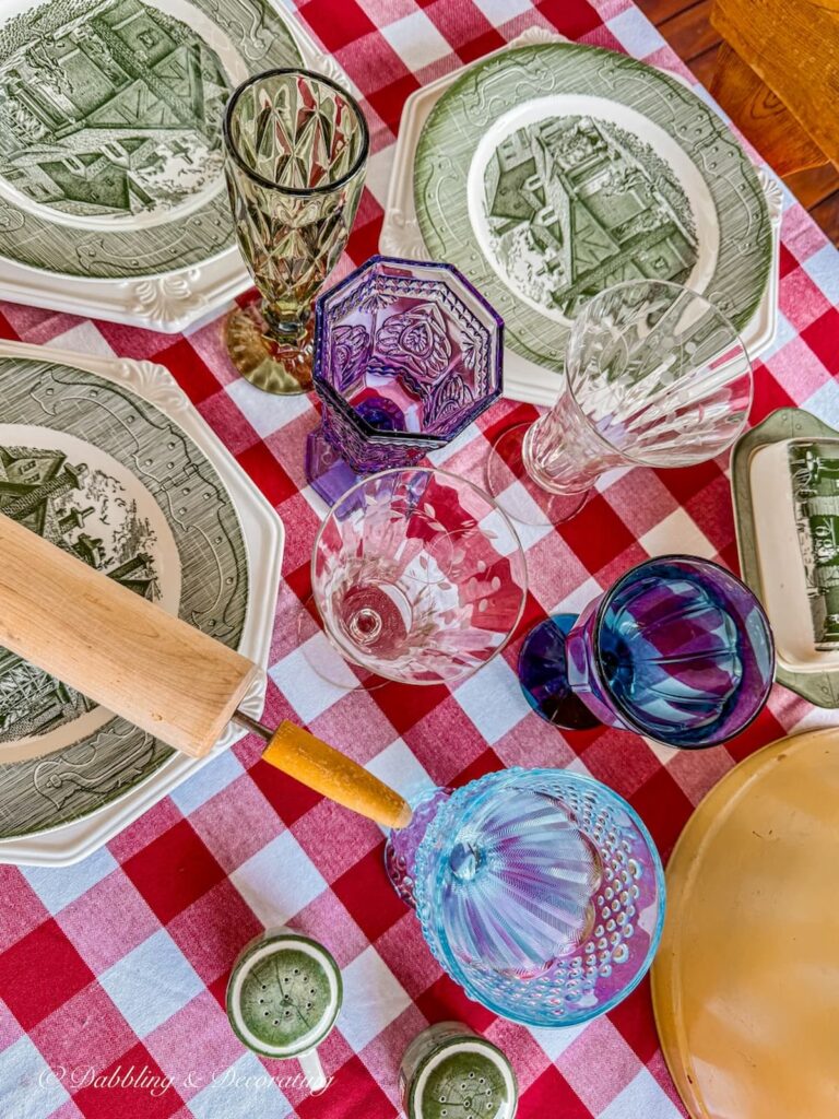 Different colored table glassware on vintage styled fall table with red and green tablewares.