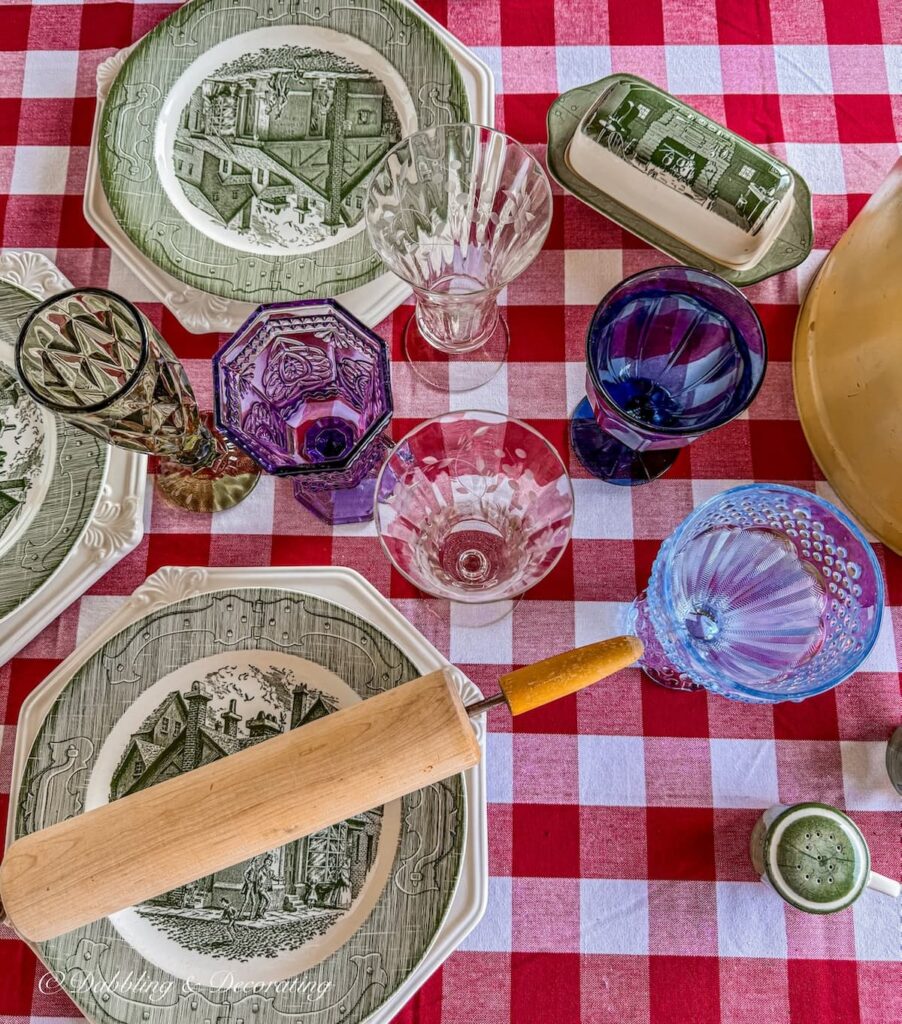 Vintage table colored glassware on red gingham table cloth in fall table decor ideas.