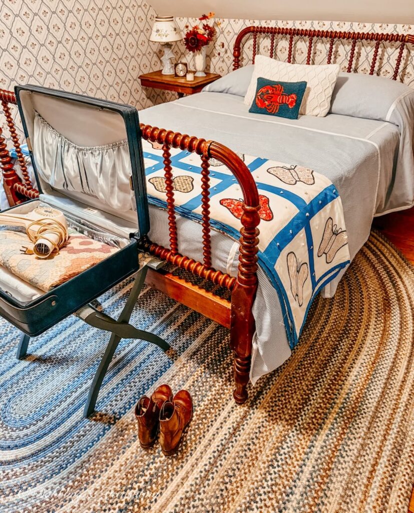Jenny Lind bed makeover layered with seerscucker bedding, antique handmade quilt and a braided rug in attic bedroom.