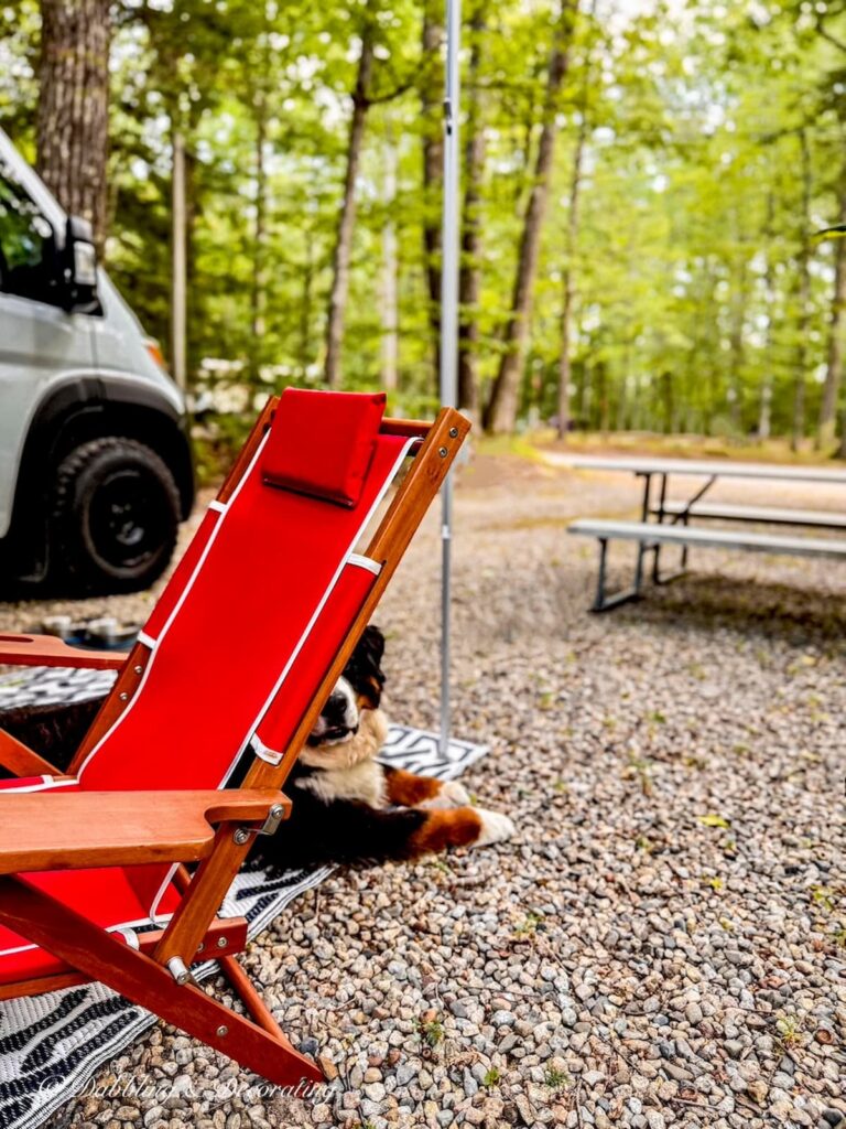 A red folding chair next to an RV at Lake Forest Resort in Southern New Hampshire with Bernese Mountain Dog.