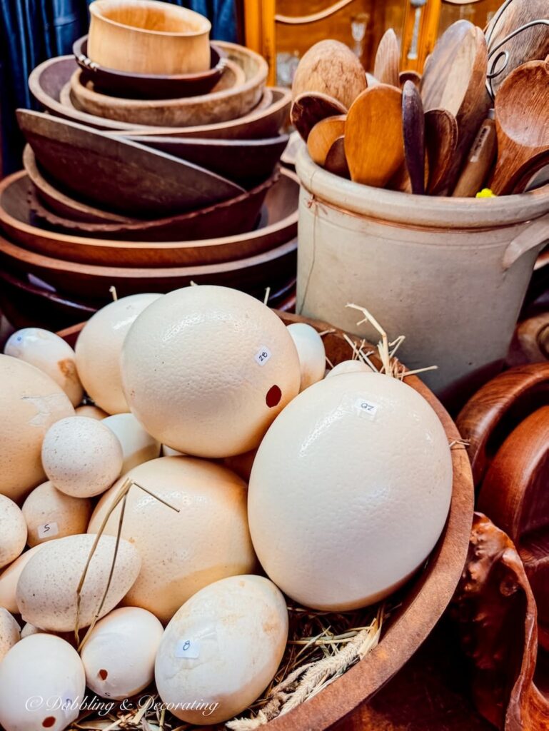 Wooden and white vintage bowls and eggs for home decor displayed in antique store.