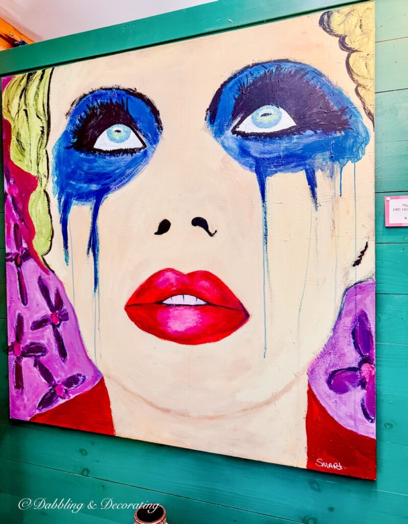 An eclectic retro painting of a woman with blue painted dripping eyes, bright red lipstick and yellow hair.