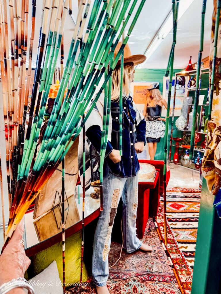 Hanging divider room beads opened looking at male mannequin with blue velvet jacket, jeans and long hair with hat.