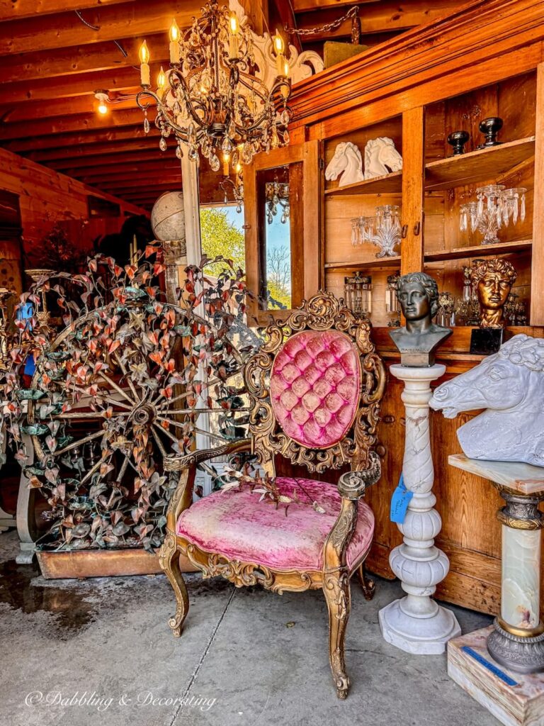 Antique pink chair in barn at RS Butler's Trading Company in Northwood, NH with chandelier. Thrifted bougie decor ideas.