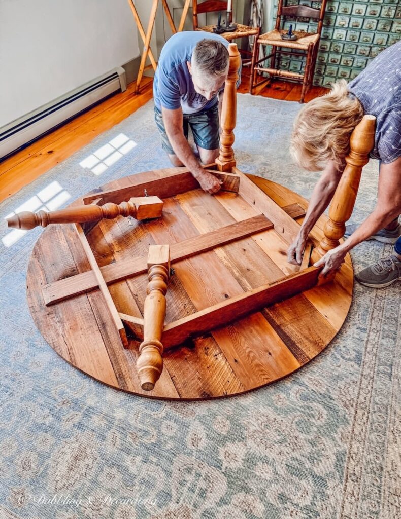 Man and woman putting handmade vintage English pine table together on dining room floor.