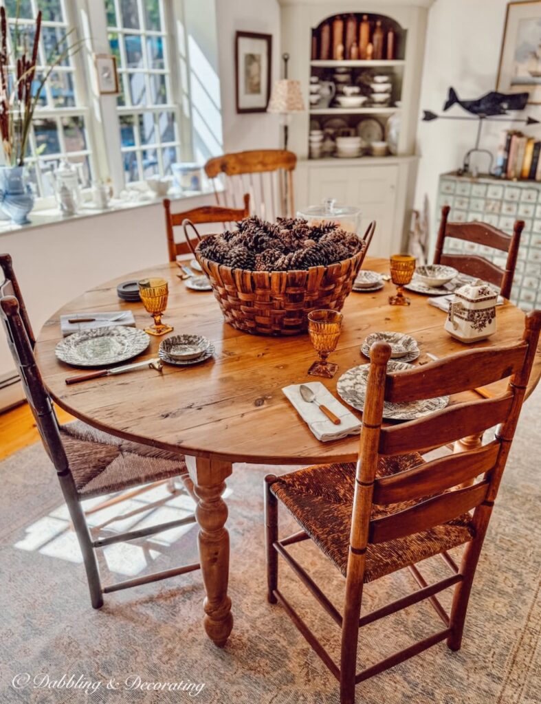 Vintage round table with ladder back chairs and fall tablescape in New England home's dining room.