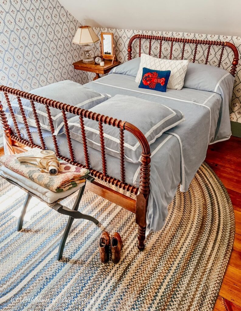 Jenny Lind bed makeover with seersucker bedding and blue braided rug in small guest bedroom in New England home.