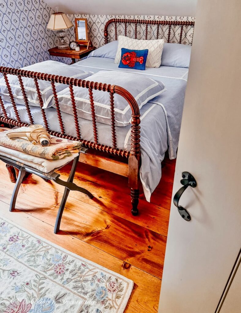 Small guest bedroom with latched door opened into a jenny lind bed makeover with seersucker bedding.