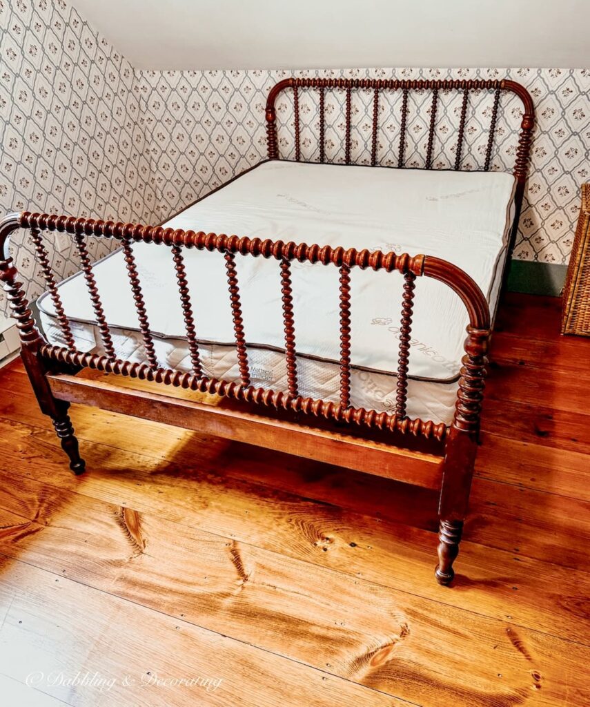Antique Jenny Lind bed makeover with custom mattress displayed in small guest bedroom with wooden flooring.