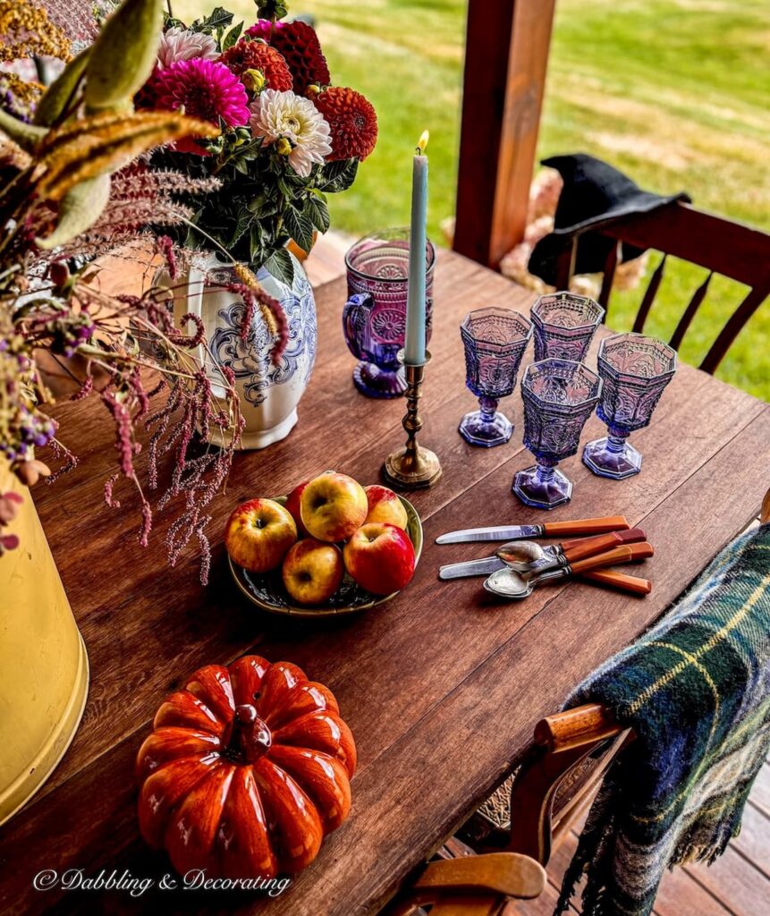 Goodwill Northern New England fall decor ideas on outdoor porch table with witch's hat hanging on chair.