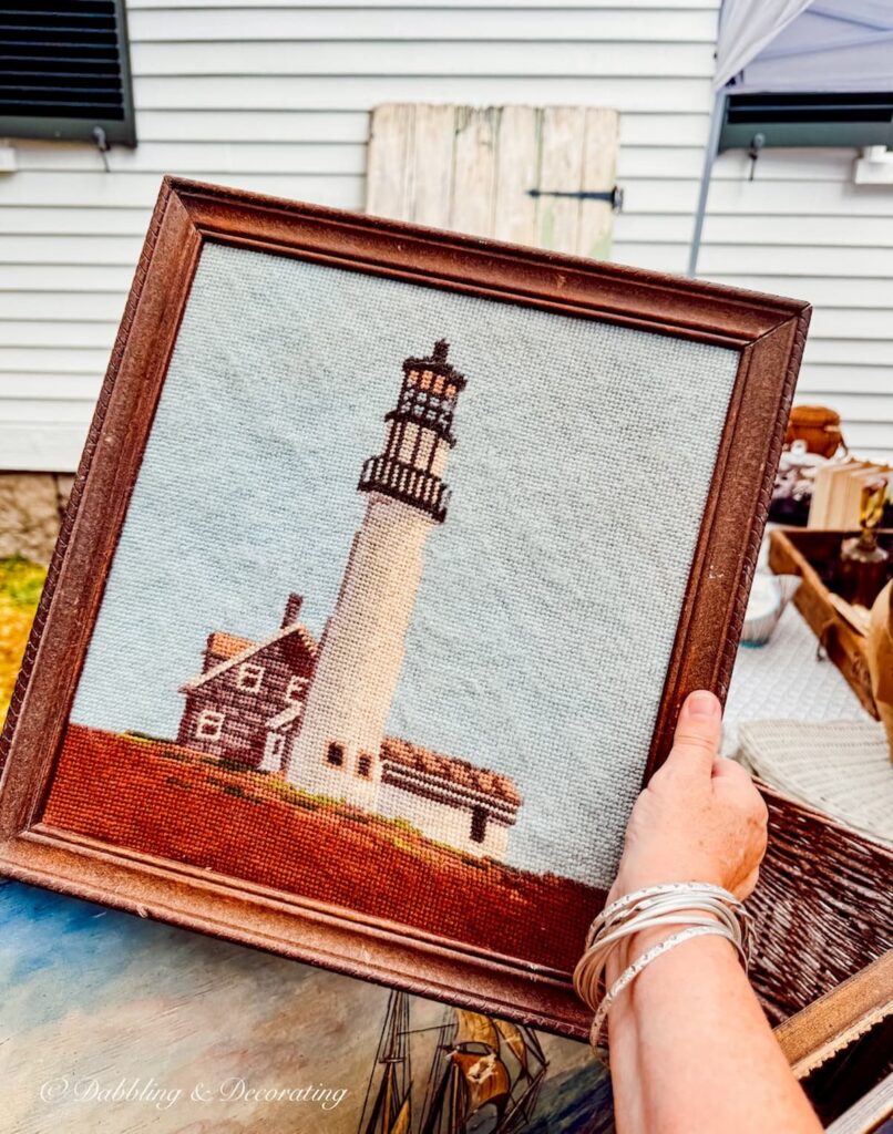 Needlepoint Seacoast lighthouse in wooden frame in hand at Vintage and Vogue Market.