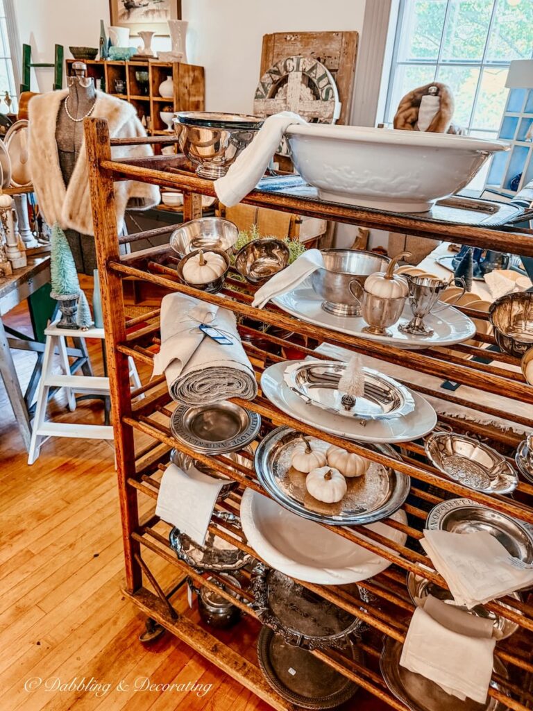 Cobbler rack filled with silver trays and ironstone at Van Claus Designs Booth at Vintage and Vogue Market in southern New Hampshire.