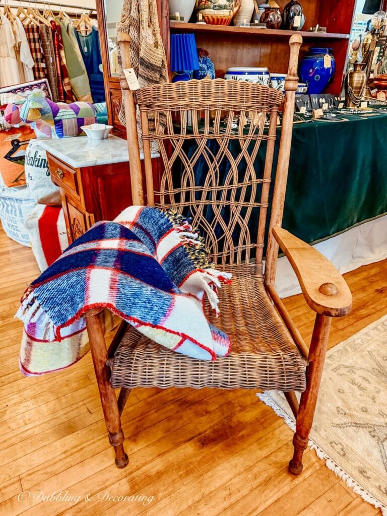 Vintage wicker large chair with vintage plaid blanket at Vintage and Vogue Market in Kensington, New Hampshire.