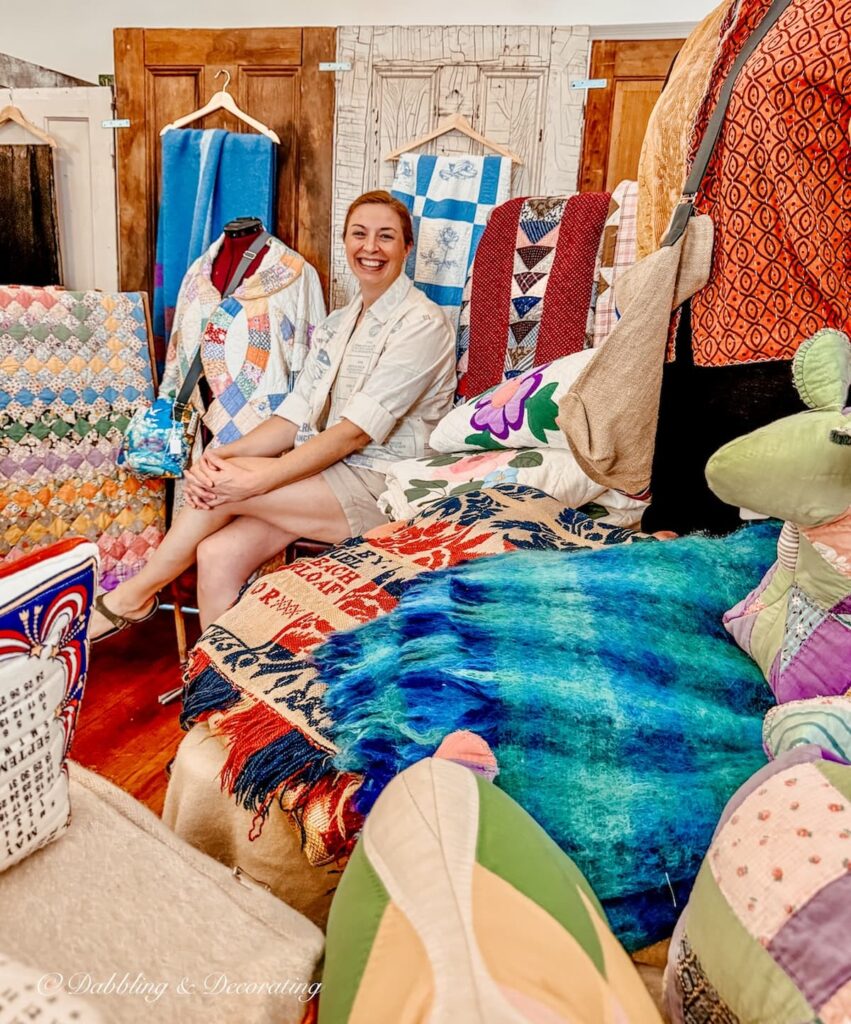 Woman sitting in a vendor booth of quilts and blankets at Vintage and Vogue Market in New Hampshire.