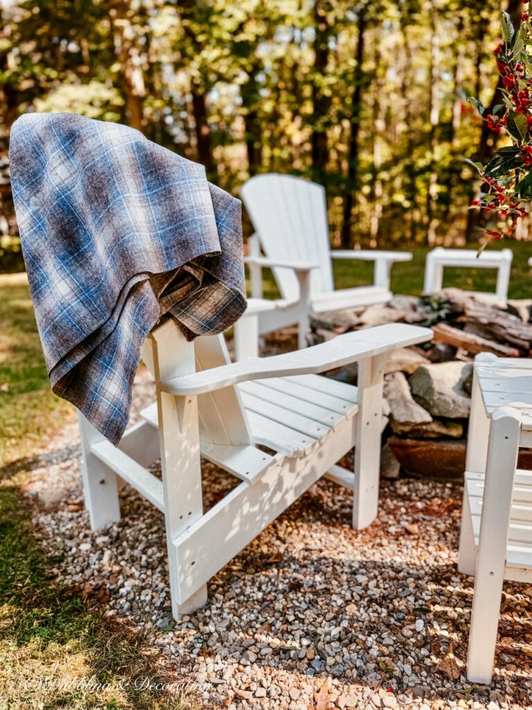 Vintage blue and brown Woolrich swatch draped over white New England Adirondack chair at a fire pit in backyard.