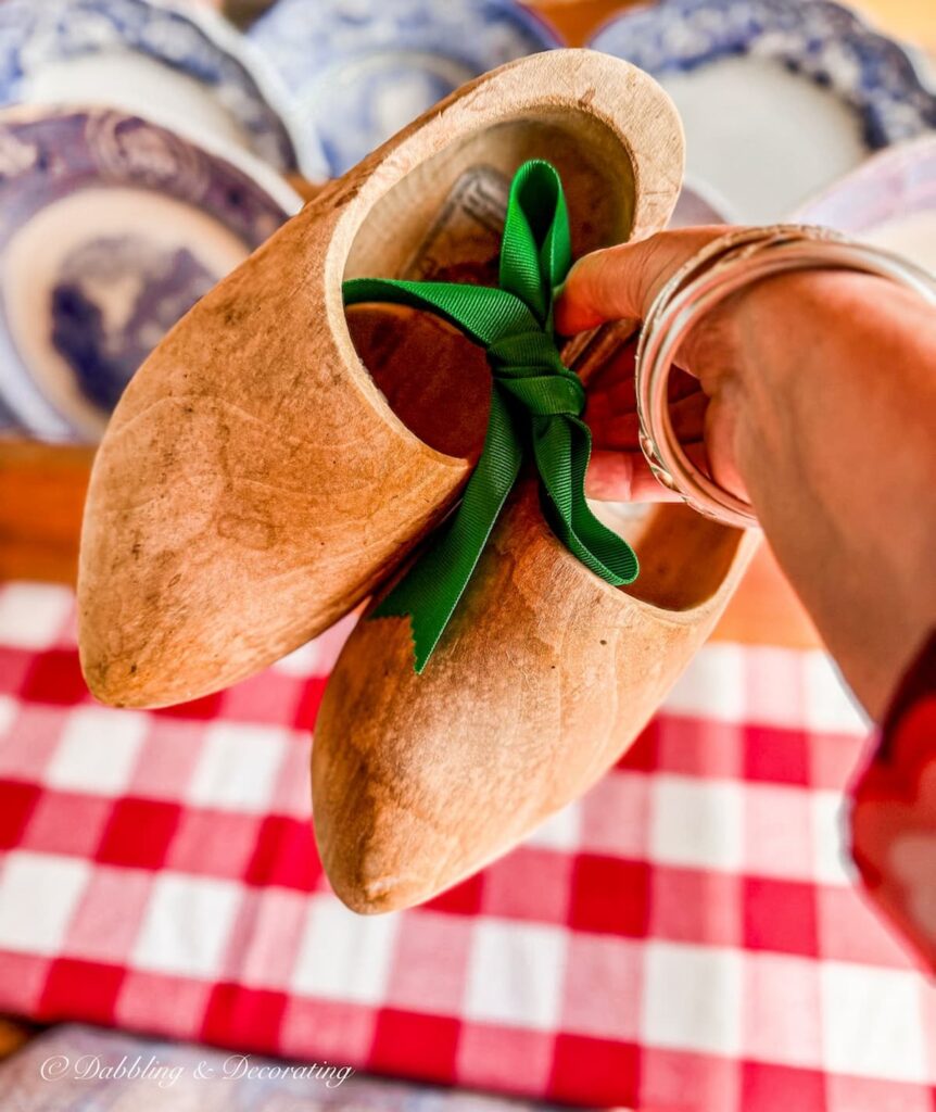 Dutch wooden clogs in hand with a green ribbon, roadside sale find.